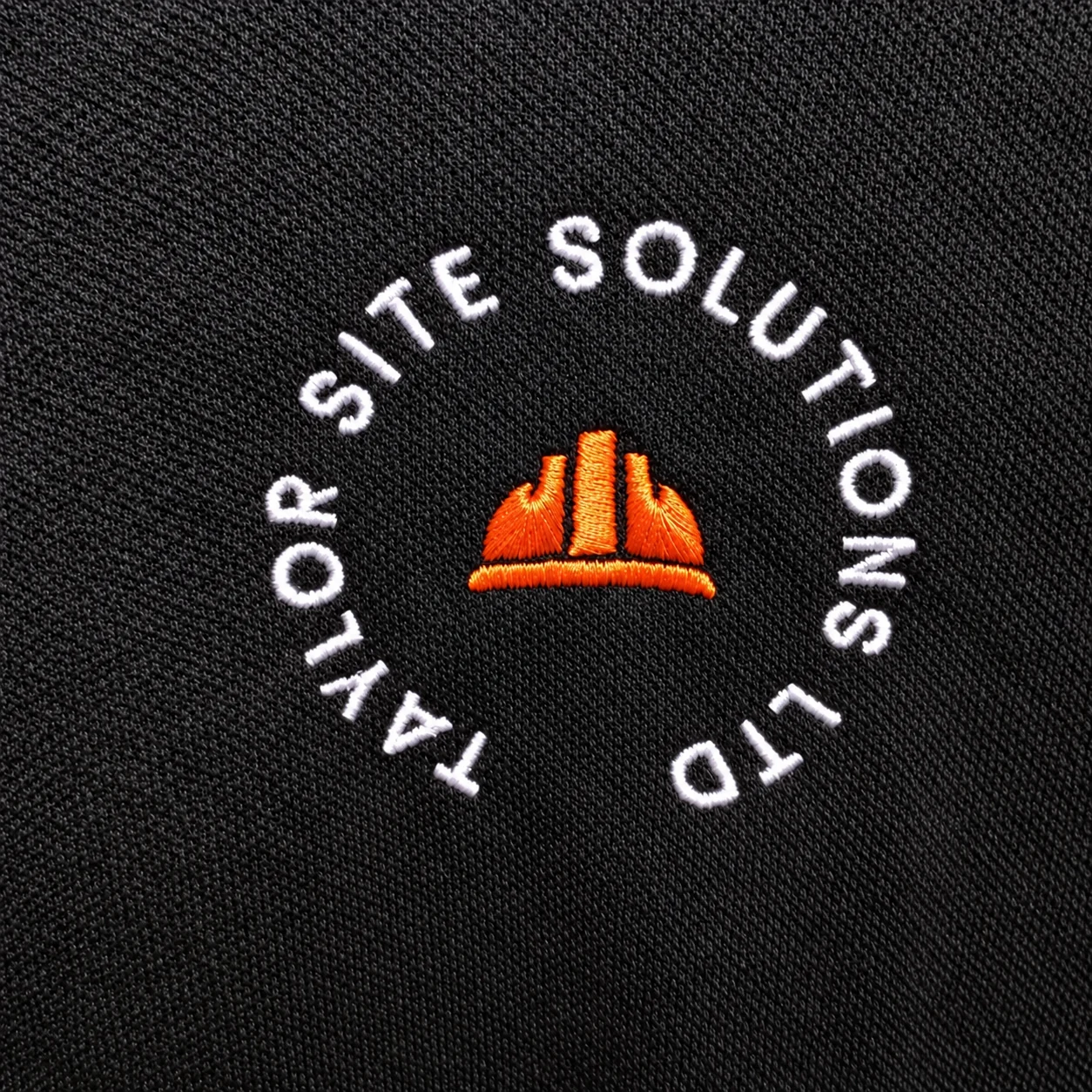 Close-up of a customer company logo embroidered on dark workwear